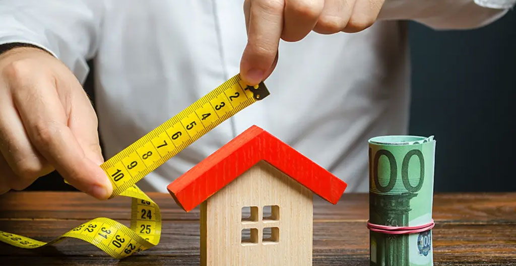 Main d'expert utilisant un mètre laser numérique pour mesurer la surface d'un appartement avec affichage digital visible